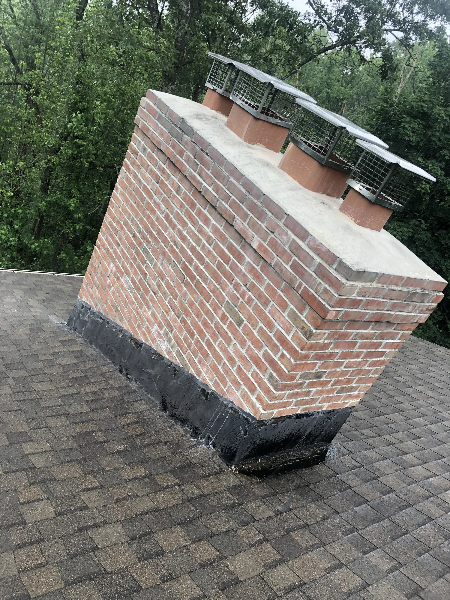 Brick chimney with a concrete crown and individual metal flue caps