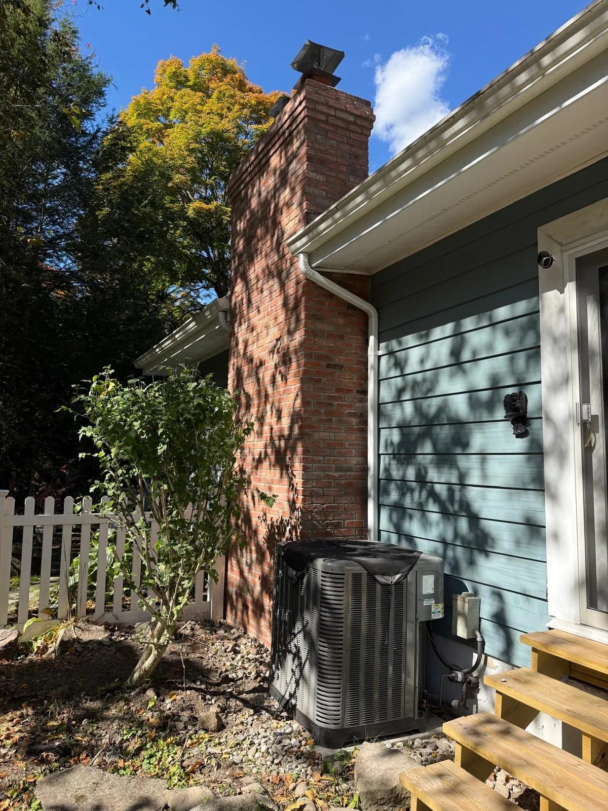 Side view of a completed brick chimney above the shingle roof